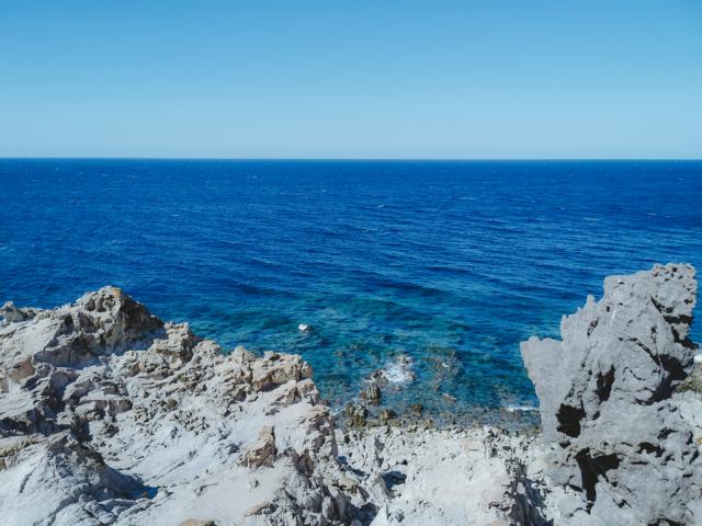 blaues Meer und karge Steine Cala Fico Isola di San Pietro Sardinien thealkamalsontheroad