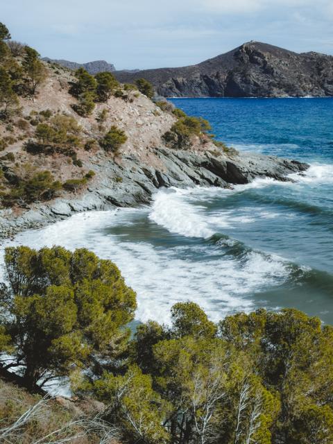hohe Wellen brechen sich am Felsen Katalonien Spanien thealkamalsontheroad