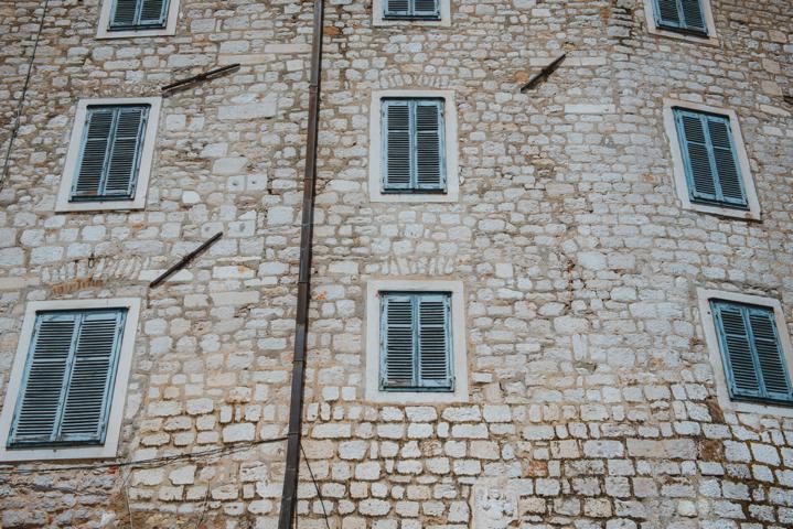 weiß-graue Ziegel mit grünen Fensterläden in Sibenik Kroatien thealkamalsontheroad