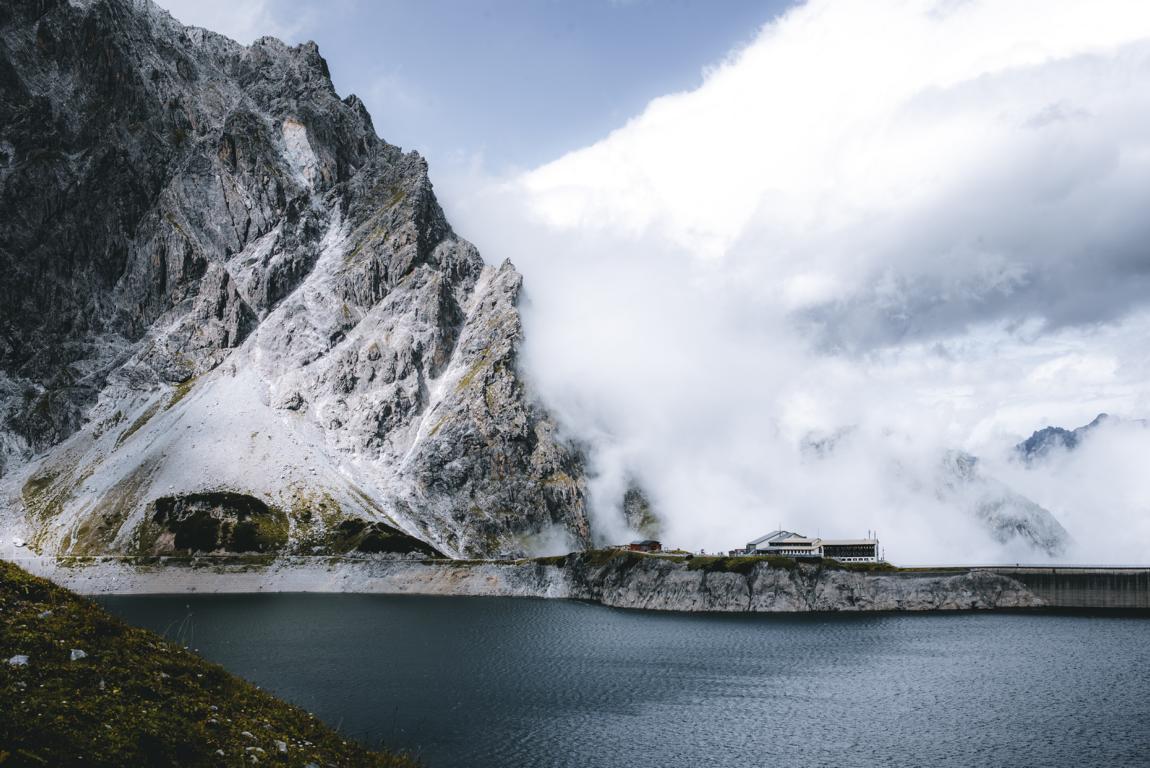 Staumauer mit Felsen und Wolken am Lünersee